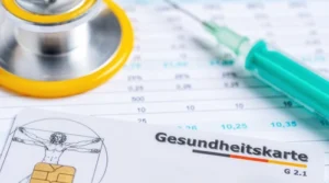 Organisation der 24h-Beatmungspflege: Eine deutsche Gesundheitskarte liegt neben einem Stethoskop und einer Spritze auf medizinischen Unterlagen.